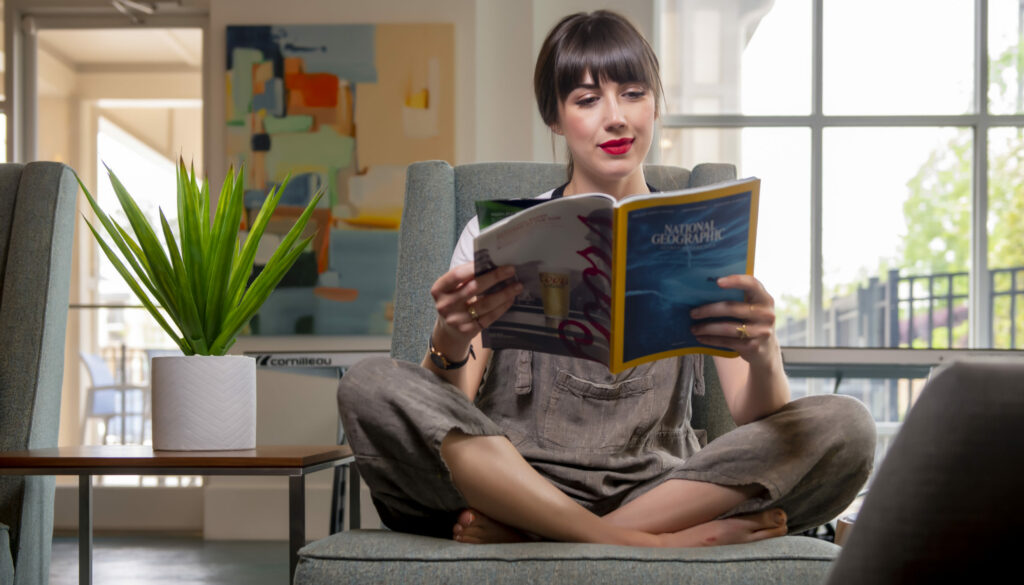 woman reading book with artificial plant apartment