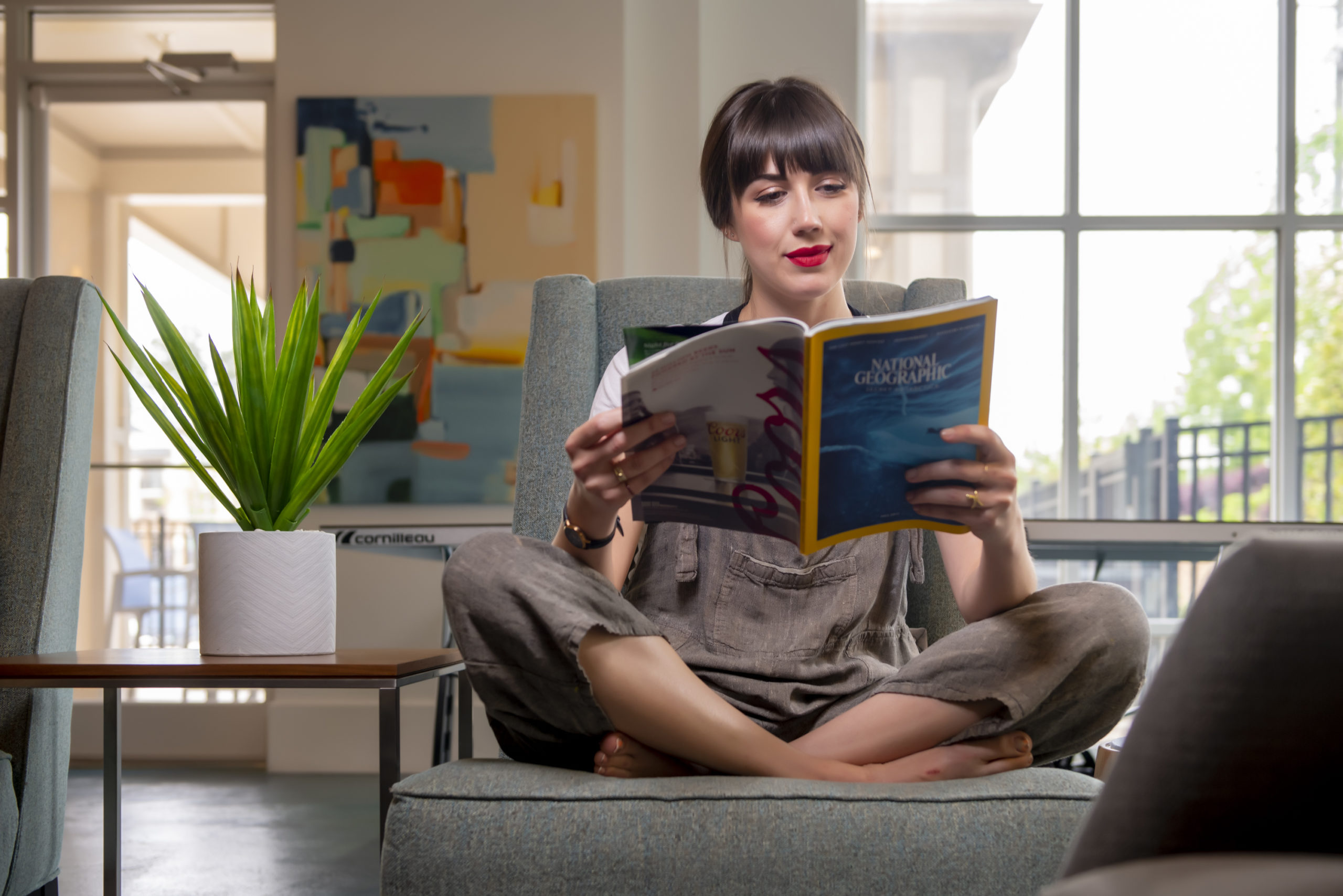 woman reading book with artificial plant apartment