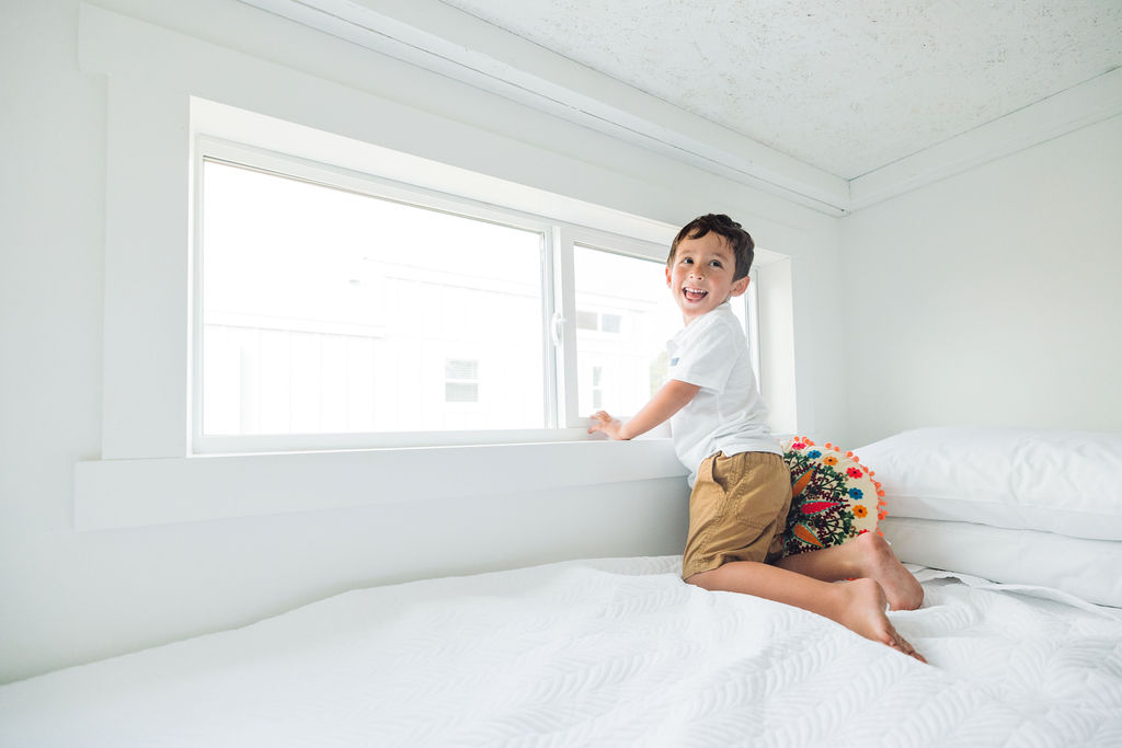 boy on bed looking out the window and smiling at oceans rv resort