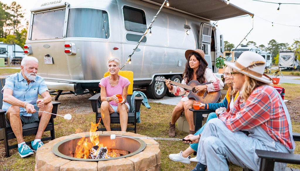 people sitting around a fire with an airstream in the background