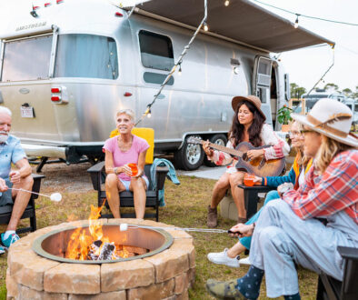 people sitting around a fire with an airstream in the background