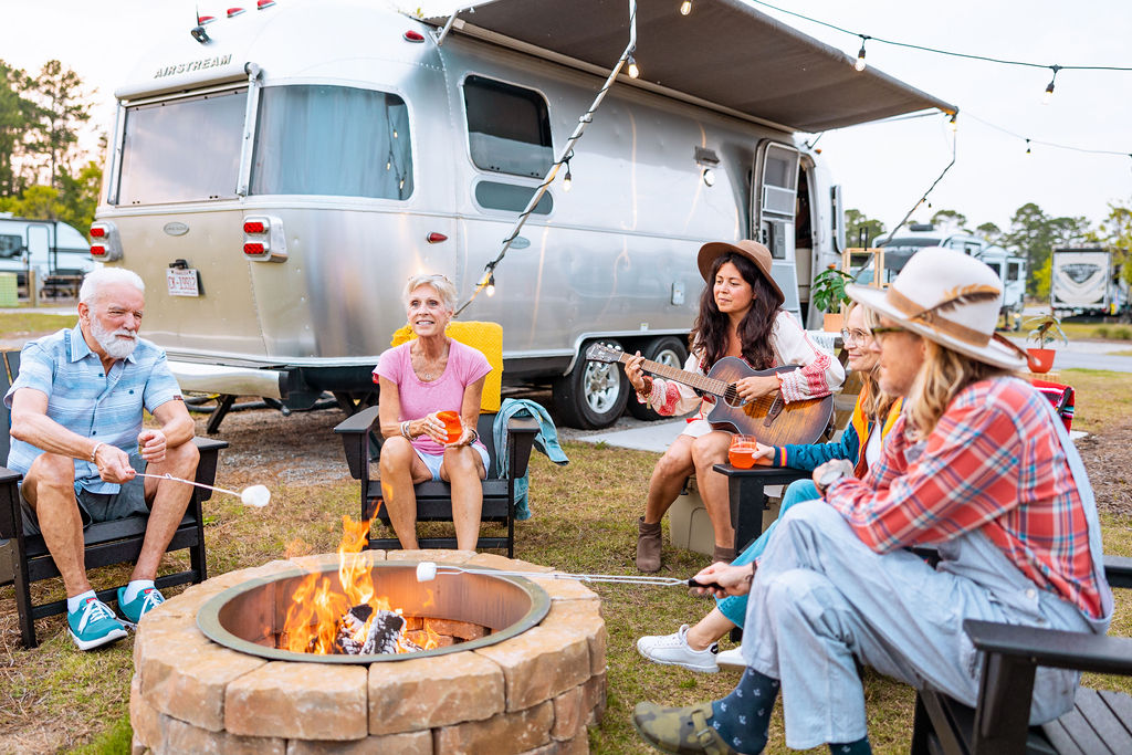 people sitting around a fire with an airstream in the background