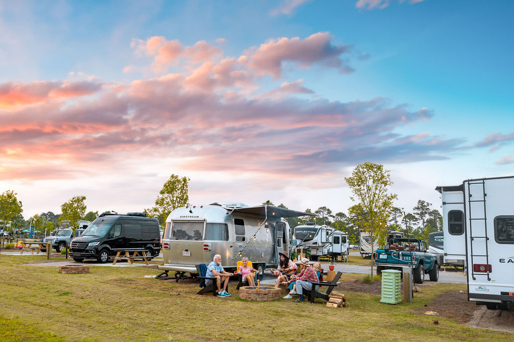 people around fire at airstream rv park at sunset