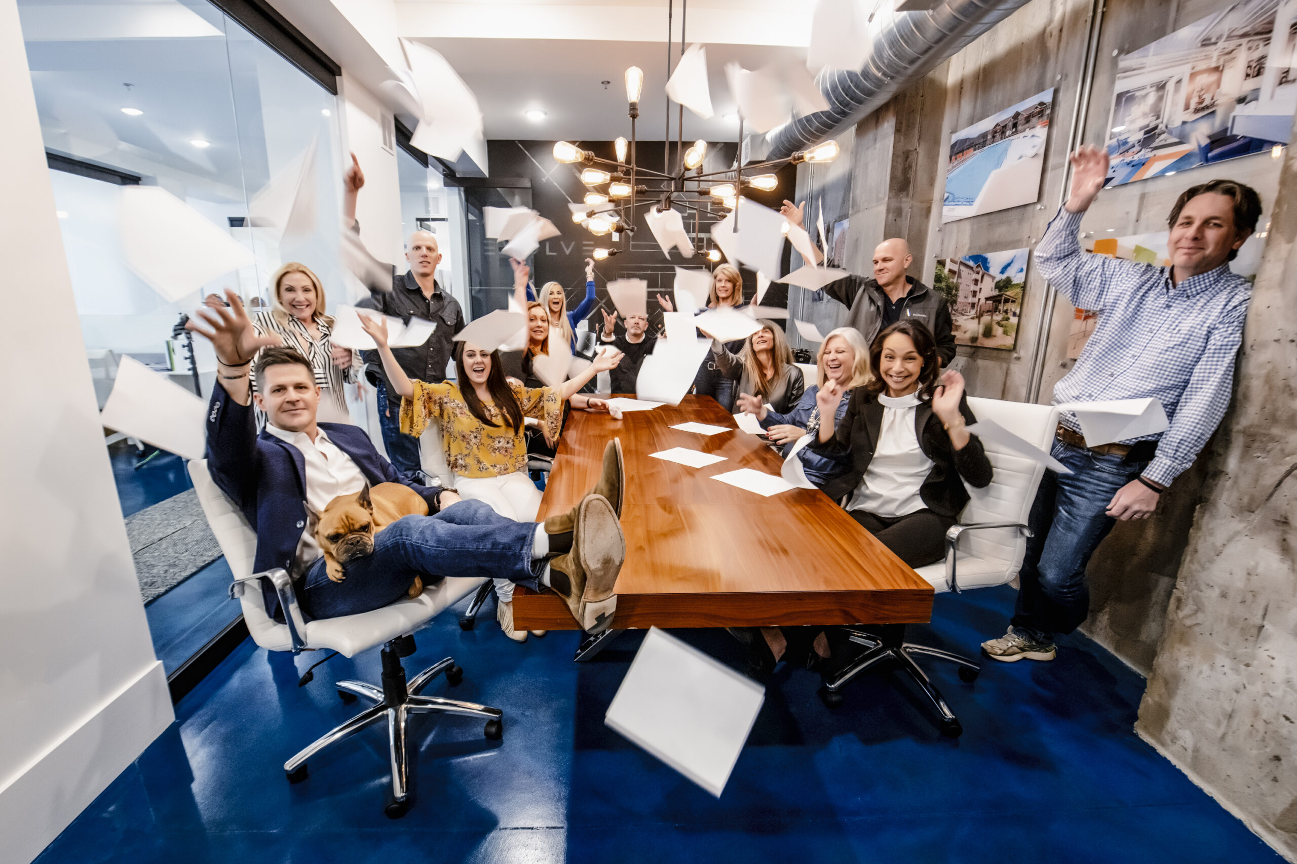 Evolve employees smiling and tossing papers in conference room